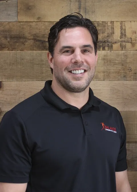 Portrait of smiling chiropractor Troy Norris in black polo shirt at Boise ID chiropractic practice.